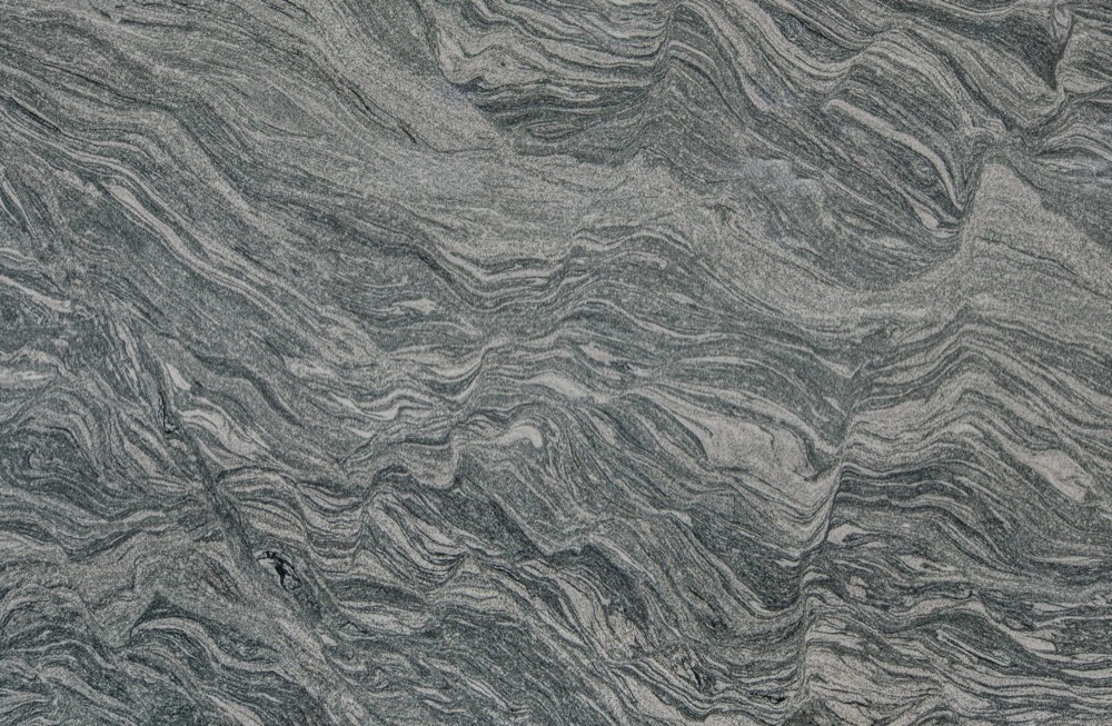 Grau-weißes Gestein mit wellenförmigen, horizontalen und diagonalen Streifen.